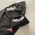Schwarze Lackleder-Schultertasche mit goldener Schleife auf grauem Sakko Anzug - Schwarz