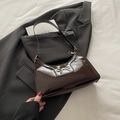 Chocolate brown patent leather shoulder bag with gold bow ornament on suit - Brown