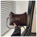 Detail of dark brown glossy leather shoulder bag with golden bow hardware and strap - Coffee