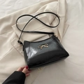Chic black glossy shoulder bag featuring a gold bow accent and slender strap - Black