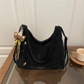 Large black minimalist hobo bag with teddy charm on a wood table in an indoor setting - Black With Pendant
