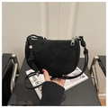 Detail of a black matte crescent bag featuring a knotted strap and chic metal letter charm - Black