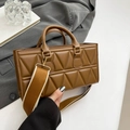 Brown quilted crossbody bag with geometric stitching and wide woven strap on neutral background - Brown