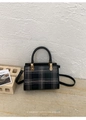 Detail of black plaid square handbag with golden hardware and cylindrical top handle - Black
