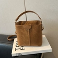 Brown suede bucket bag with top handle and adjustable strap on a book display - No Pendant / Brown