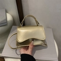 Mini bolso dorado metalizado con asa superior y correa en una escena de estilo de vida - Dorado