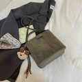 Dunkelgrüne Wildleder-Eimertasche mit Bärenanhänger auf einem grauen Blazer - Grün (Mit Anhänger)