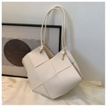 Detail einer beige geflochtenen Tragetasche mit geknoteten Riemen und Goldakzenten - Beige