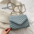 Elegant light blue quilted crossbody bag with golden chain strap on a soft fabric base - Blue