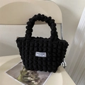 Black popcorn fabric shoulder bag with FASHION INSTINCT label on a beige chair - Black without Pendant