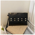 Close-up of black envelope clutch bag with gold hexagon rivets and a side wrist strap - Black