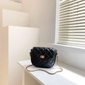 Elegant black quilted saddle bag featuring a gold twist lock and woven chain strap - Black