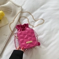 Borsa a secchiello trapuntata rosa con catena dorata e coulisse in un ambiente domestico - Rosa Rosso