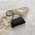 Chic black envelope shoulder bag with matte texture and gold metal accents on beige blazer - Black
