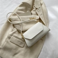 Elegante bolso baguette blanco con textura en relieve y detalles metálicos dorados - Blanco