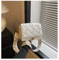 Detail of white quilted handbag featuring a wide textile strap with golden hardware - White