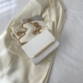 Elegante borsa a tracolla bianca con catena d'oro su un blazer minimalista - Bianco
