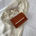 Borsa a tracolla marrone caramello minimalista con catena dorata su blazer bianco - Marrone