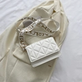 White quilted crossbody flap bag with a wide patterned strap on a beige textured blazer - White