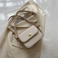 Minimalistische beige Umhängetasche mit goldenem Herzverschluss auf Blazer-Hintergrund - Weiß