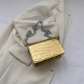 Glossy gold crocodile pattern square bag with metallic chain strap on white blazer - Gold