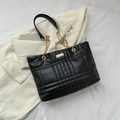 Quilted black faux leather tote bag with gold chain handles and metallic emblem - Black