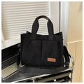 Detailed close-up of a black corduroy tote bag with double front pockets and brown logo - Black
