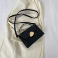 Borsa a mano strutturata in pelle nera con fibbia dorata su un blazer crema elegante - Nero