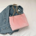 Pink suede tote bag with woven texture and thin beige handles on denim background - Pink