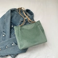 Green checkerboard embossed suede tote bag with slim khaki straps on denim background - Green