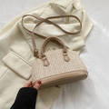 Gewebte Muschel-Handtasche in Cremeweiß mit Khaki-Besatz auf einem schicken Sakko - Khaki