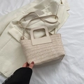 Sac seau en paille beige avec poignées en cuir sur un fond blanc minimaliste - Blanc