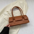 Bolso de hombro de cuero sintético marrón con asas finas sobre fondo de traje crema - Marrón