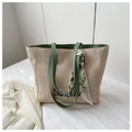 Detail of a beige woven straw tote bag with green leather handles and a silk scarf - Green