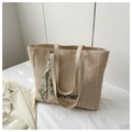 Close-up of woven straw tote bag featuring summer embroidery and a decorative silk scarf - White