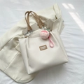 Off-white tote bag with brown handles, silver chain, and peach plush charm accessory - With Pendant / White & Khaki