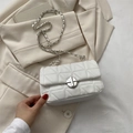 Sac bandoulière matelassé blanc élégant avec chaîne argentée sur un blazer beige - Style Matelassé / Blanc