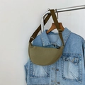 Detail of olive green crescent crossbody bag styled on a denim jacket for casual look - Green