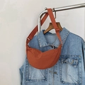 Detailed shot of a brick red crescent crossbody bag with adjustable wide strap on hanger - Orange