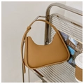 Sac hobo croissant caramel avec bandoulière réglable sur une étagère en métal - Kaki