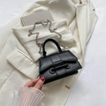 Mini sac noir en cuir mat avec chaîne argentée posé sur un tailleur blanc élégant - Noir