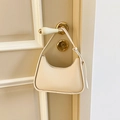 Sleek creamy white hobo bag with gold hardware hanging on a door handle - White