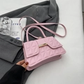Pink quilted crossbody handbag with gold hardware and top handle over grey blazer - Pink