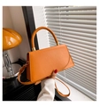 Detail of a bright orange crossbody bag with gold hardware and curved flap design - Yellow Brown