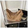 Close-up of brown corduroy tote bag showing metal buckle and brand leather patch - Khaki