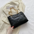 Schwarze gesteppte Puffer-Handtasche mit goldener Kette auf minimalistischem Hintergrund - Schwarz