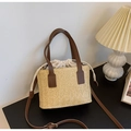 Detalle del bolso tipo cubo de paja tejida con textura y correa de cuero marrón - Marrón