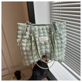 Close-up of mint green bubble textured bag with silver chain and leather logo patch - Green