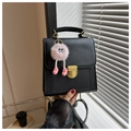 Détail d'un sac à dos en cuir noir mat avec fermoir doré et un pendentif en peluche rose - Avec Pendentif / Noir