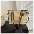 Détail du sac cabas en paille tressée avec bordure en cuir marron et boucles dorées - café